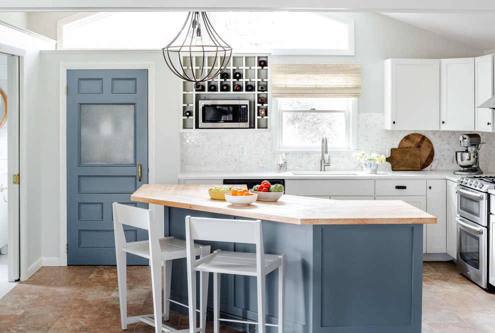 Inspiration for a mid-sized beach style l-shaped eat-in kitchen in Portland Maine with an undermount sink, shaker cabinets, white cabinets, wood benchtops, white splashback, mosaic tile splashback, stainless steel appliances, slate floors, with island and brown floor.