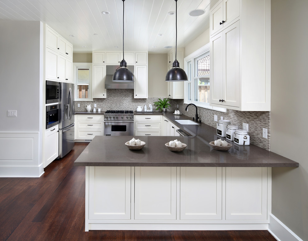 Example of a mid-sized transitional u-shaped medium tone wood floor eat-in kitchen design in San Francisco with a drop-in sink, shaker cabinets, white cabinets, quartz countertops, beige backsplash, mosaic tile backsplash, stainless steel appliances and a peninsula