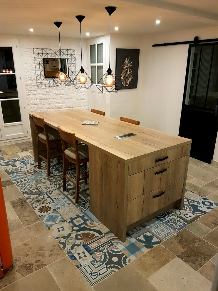 Mid-sized midcentury single-wall open plan kitchen in Montpellier with a farmhouse sink, multi-coloured splashback, stainless steel appliances, cement tiles, with island, multi-coloured floor, beaded inset cabinets, medium wood cabinets, wood benchtops, cement tile splashback and brown benchtop.