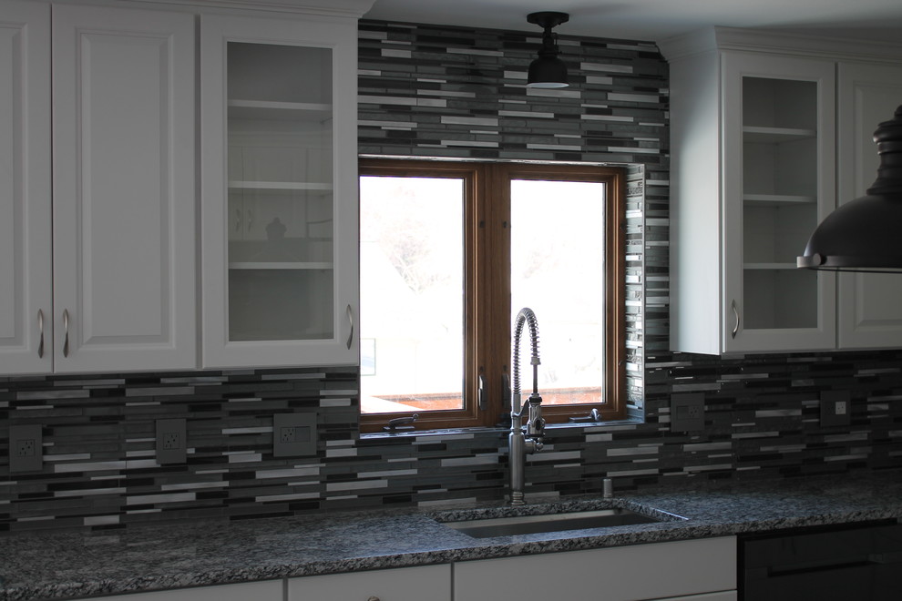 Mid-sized transitional u-shaped dark wood floor and brown floor kitchen photo with an undermount sink, raised-panel cabinets, white cabinets, granite countertops, multicolored backsplash, matchstick tile backsplash, stainless steel appliances and an island