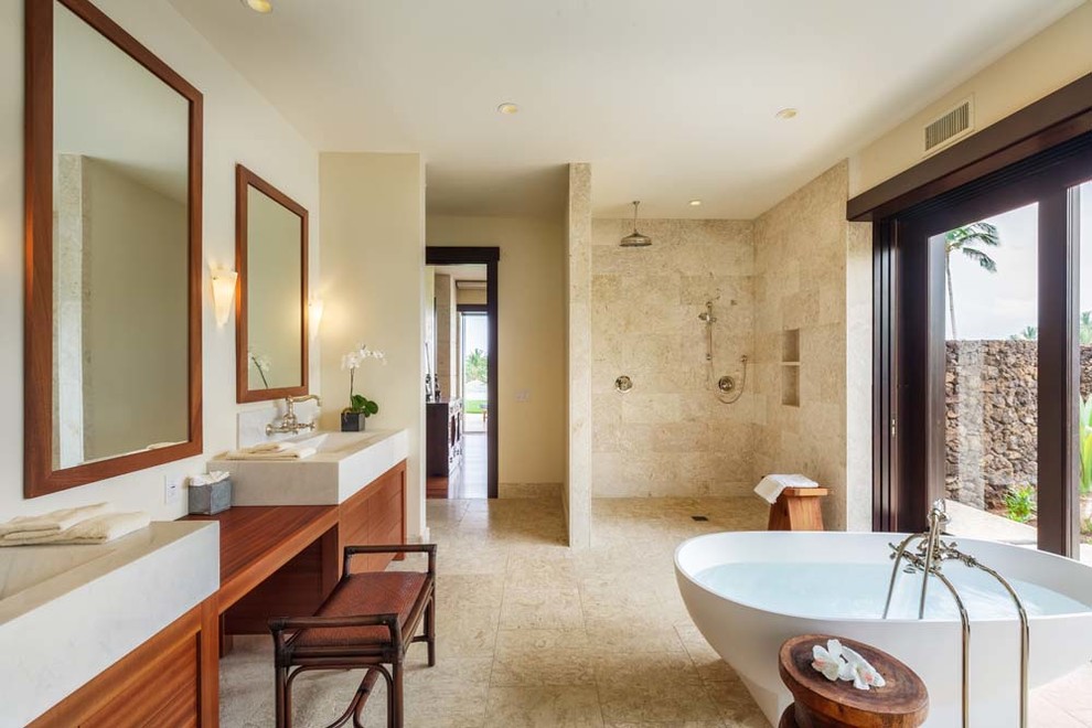 Inspiration for a large contemporary master bathroom in Hawaii with flat-panel cabinets, medium wood cabinets, an open shower, a freestanding tub, beige tile, stone tile, beige walls, travertine floors, an integrated sink, wood benchtops, beige floor and an open shower.