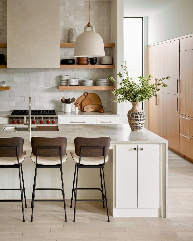 Inspiration for a mid-sized contemporary single-wall eat-in kitchen in Austin with a drop-in sink, open cabinets, light wood cabinets, limestone benchtops, white splashback, stone tile splashback, stainless steel appliances, light hardwood floors, with island, beige floor and beige benchtop.