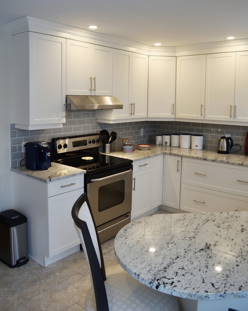Enclosed kitchen - mid-sized transitional u-shaped ceramic tile enclosed kitchen idea in Ottawa with an undermount sink, shaker cabinets, white cabinets, granite countertops, gray backsplash, glass tile backsplash, stainless steel appliances and a peninsula