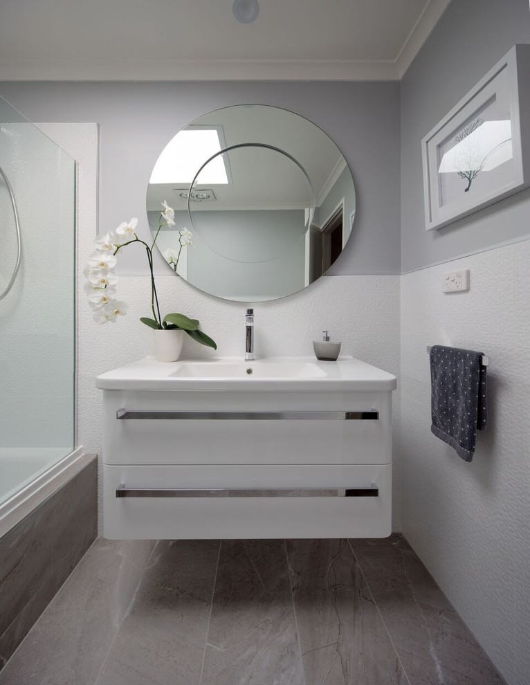 Inspiration for a small modern 3/4 bathroom in Melbourne with open cabinets, white cabinets, a drop-in tub, a shower/bathtub combo, gray tile, ceramic tile, white walls, porcelain floors, an integrated sink and soapstone benchtops.