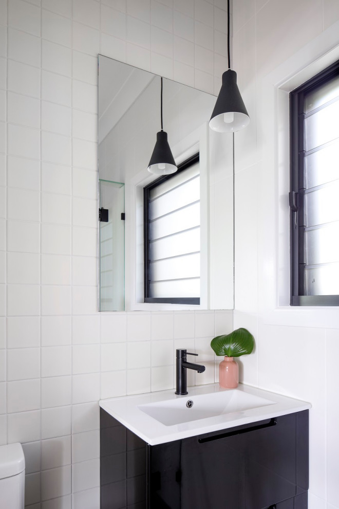 Inspiration for a small midcentury powder room in Townsville with flat-panel cabinets, black cabinets, white tile, ceramic tile, white walls, an integrated sink, solid surface benchtops and white benchtops.