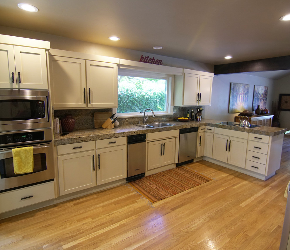 Inspiration for a mid-sized transitional u-shaped eat-in kitchen in Sacramento with a double-bowl sink, shaker cabinets, white cabinets, granite benchtops, stainless steel appliances, light hardwood floors, a peninsula, beige floor and beige benchtop.
