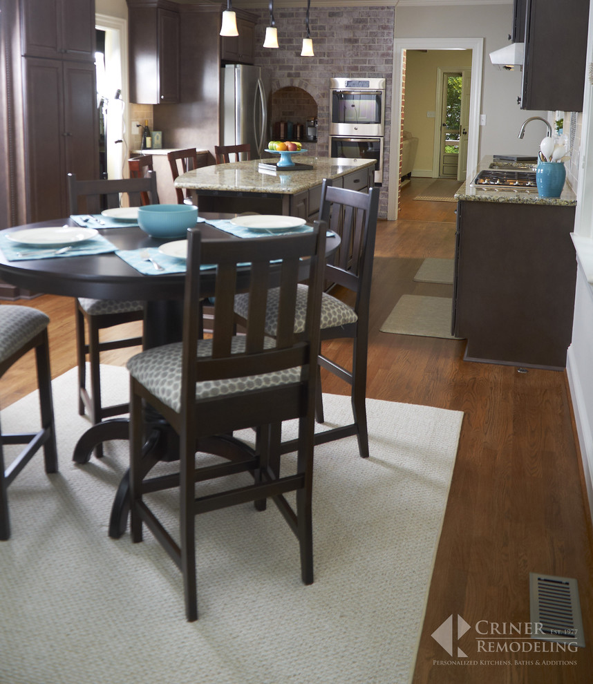Eat-in kitchen - transitional light wood floor eat-in kitchen idea with shaker cabinets, dark wood cabinets, granite countertops, beige backsplash, glass tile backsplash, stainless steel appliances and an island