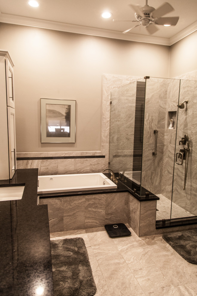 Example of a mid-sized transitional master gray tile and ceramic tile marble floor, gray floor and double-sink drop-in bathtub design with shaker cabinets, white cabinets, a two-piece toilet, gray walls, an undermount sink, quartzite countertops, a hinged shower door, black countertops, a niche and a floating vanity