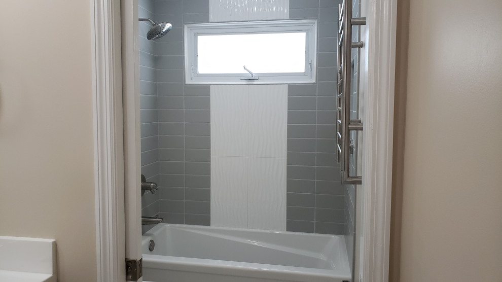 This is an example of a mid-sized midcentury 3/4 bathroom in Chicago with flat-panel cabinets, grey cabinets, an alcove shower, a two-piece toilet, gray tile, beige walls, ceramic floors, an integrated sink, marble benchtops, grey floor, a shower curtain and white benchtops.