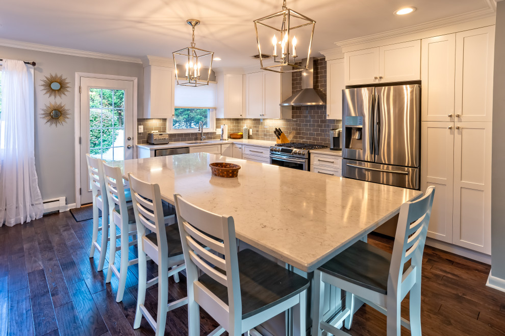 Inspiration for a mid-sized transitional l-shaped porcelain tile and brown floor eat-in kitchen remodel in Philadelphia with an undermount sink, shaker cabinets, white cabinets, quartz countertops, gray backsplash, porcelain backsplash, stainless steel appliances and gray countertops