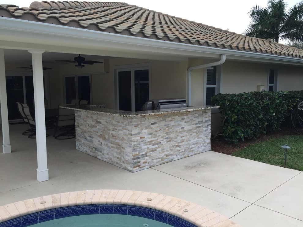 Photo of a mid-sized tropical backyard patio in Miami with an outdoor kitchen, concrete slab and a roof extension.