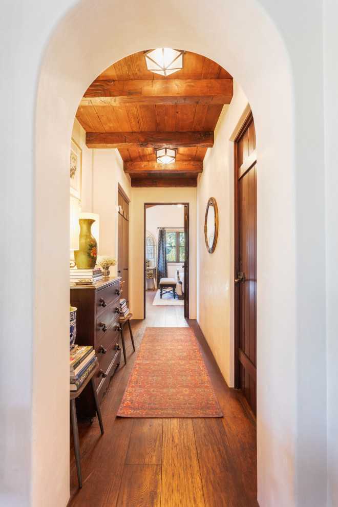 Inspiration for a small mediterranean hallway in Santa Barbara with white walls, medium hardwood floors and exposed beam.