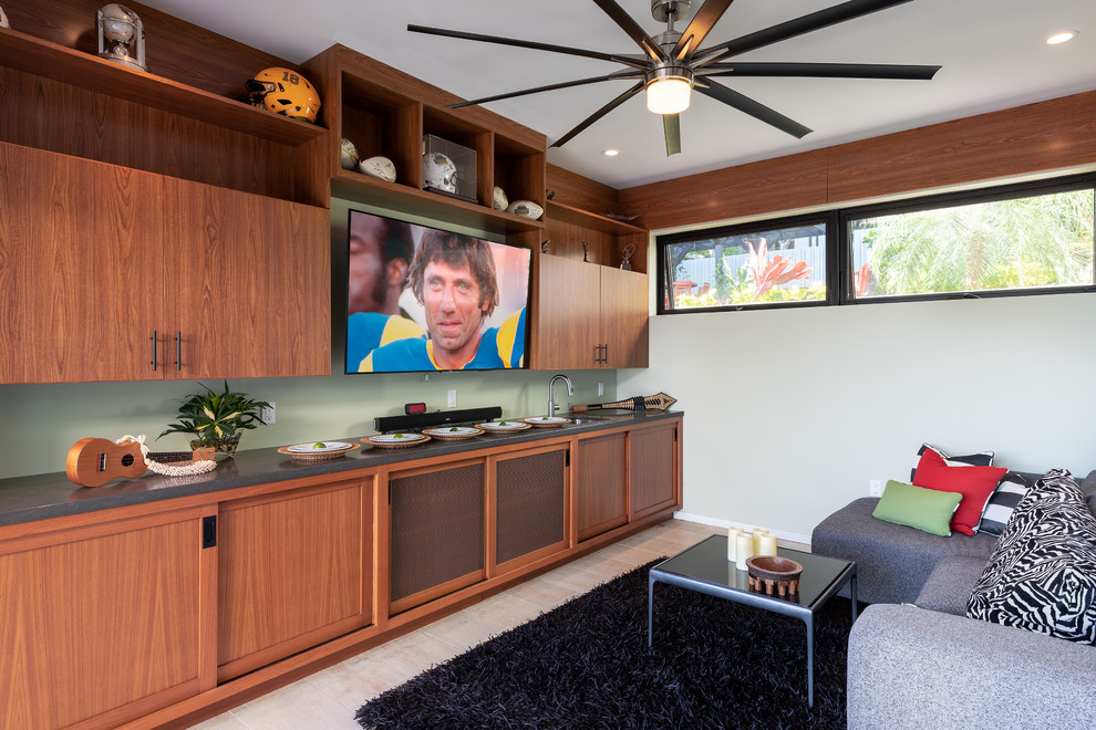 This is an example of a mid-sized tropical open concept family room in Hawaii with beige walls, ceramic floors, no fireplace, a wall-mounted tv and beige floor.