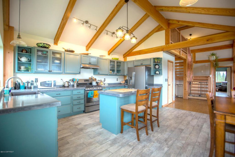 Photo of a large country u-shaped eat-in kitchen in Other with a farmhouse sink, recessed-panel cabinets, turquoise cabinets, concrete benchtops, grey splashback, stone tile splashback, stainless steel appliances, ceramic floors, with island, grey floor, grey benchtop and wood.