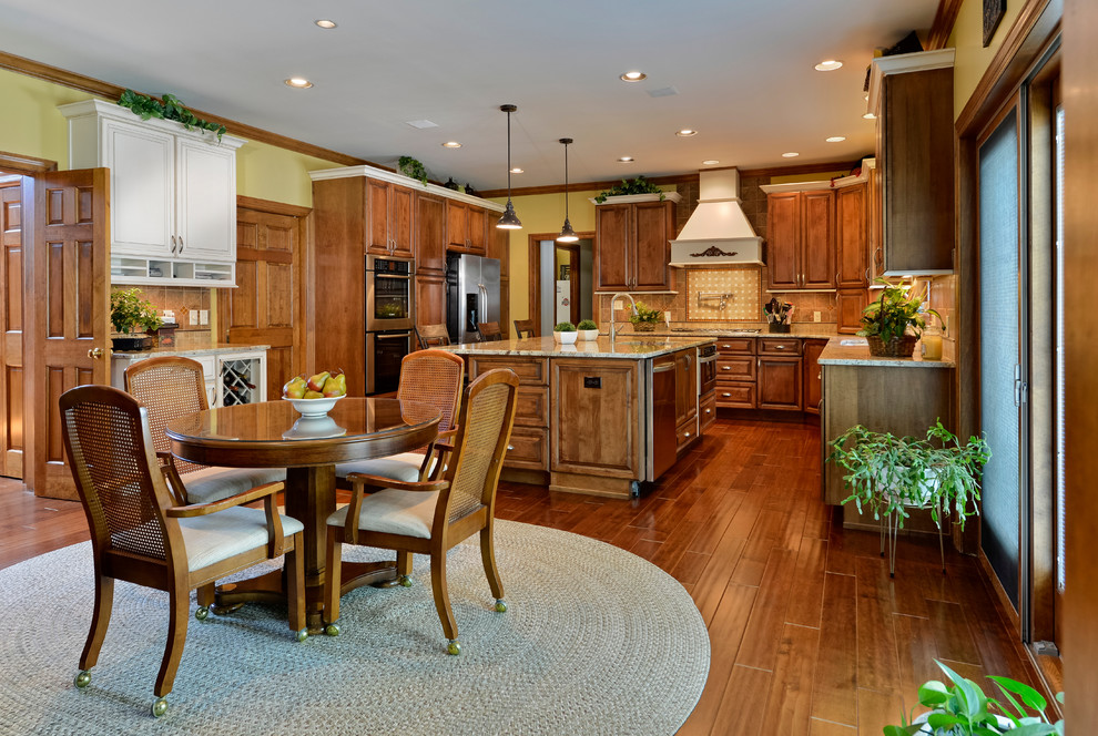 Large transitional u-shaped medium tone wood floor eat-in kitchen photo with beaded inset cabinets, medium tone wood cabinets, granite countertops, beige backsplash, mosaic tile backsplash, stainless steel appliances and an island