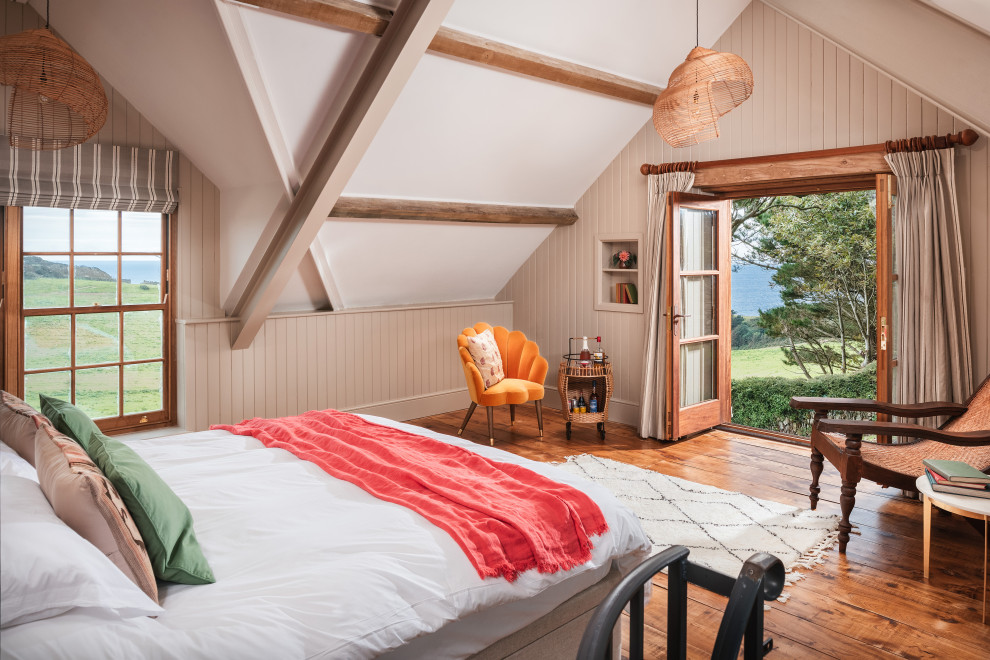 Diseño de dormitorio principal campestre grande con paredes beige, suelo de madera en tonos medios y panelado
