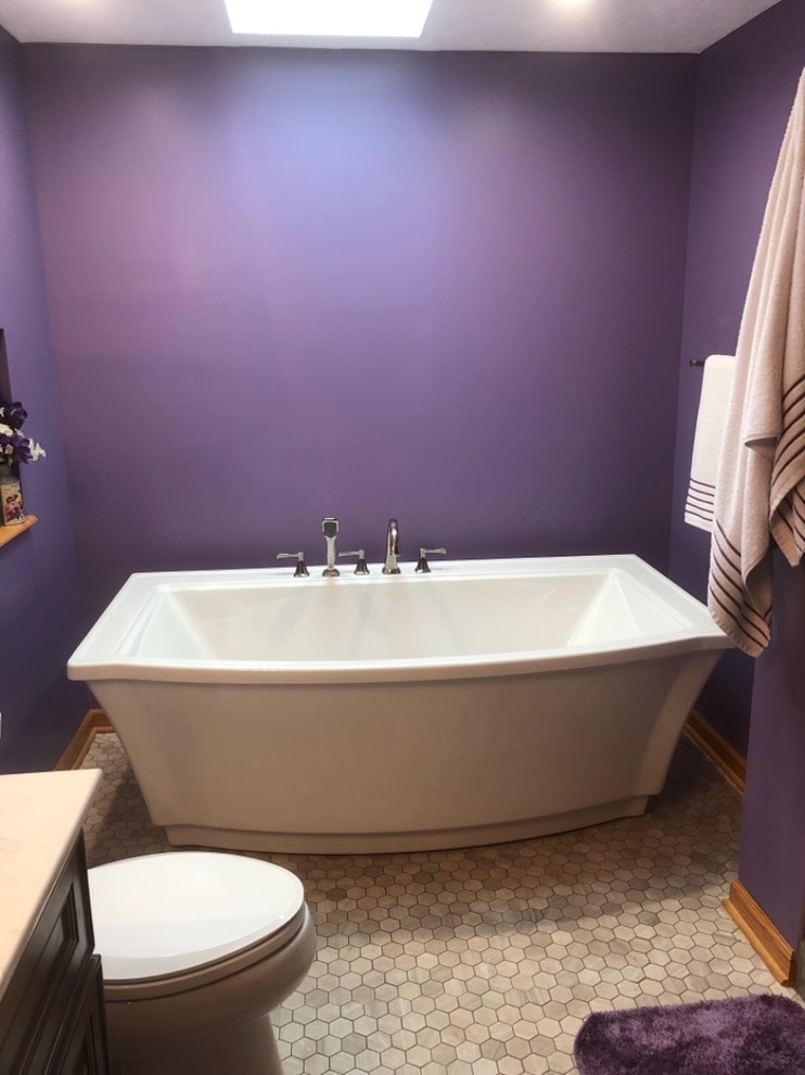 This is an example of a large traditional master bathroom in Cleveland with flat-panel cabinets, brown cabinets, a freestanding tub, an alcove shower, a two-piece toilet, gray tile, ceramic tile, purple walls, porcelain floors, an integrated sink, engineered quartz benchtops, white floor, a hinged shower door and white benchtops.