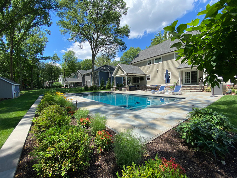 Immagine di un grande patio o portico chic dietro casa con pavimentazioni in pietra naturale e un tetto a sbalzo