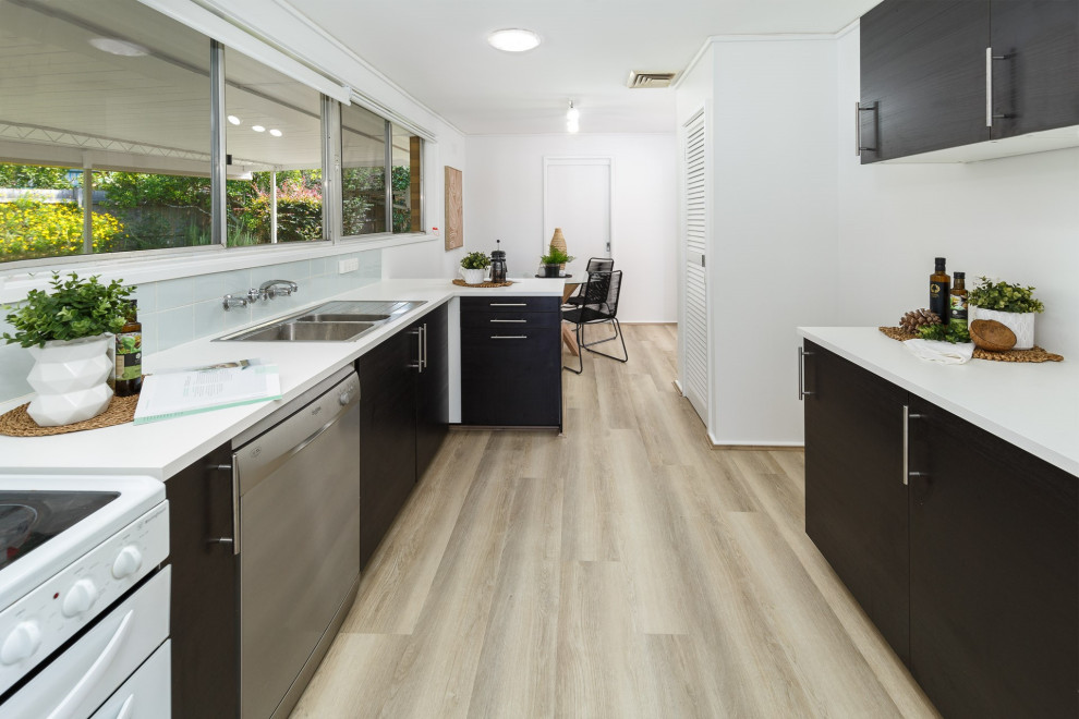Inspiration for a mid-sized transitional galley open plan kitchen in Sydney with quartz benchtops, white splashback, laminate floors and black benchtop.