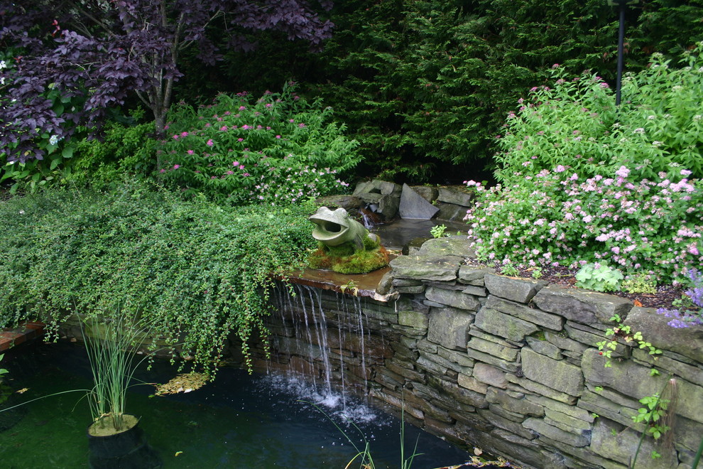 Photo of a large transitional backyard custom-shaped natural pool in New York with a water feature and natural stone pavers.