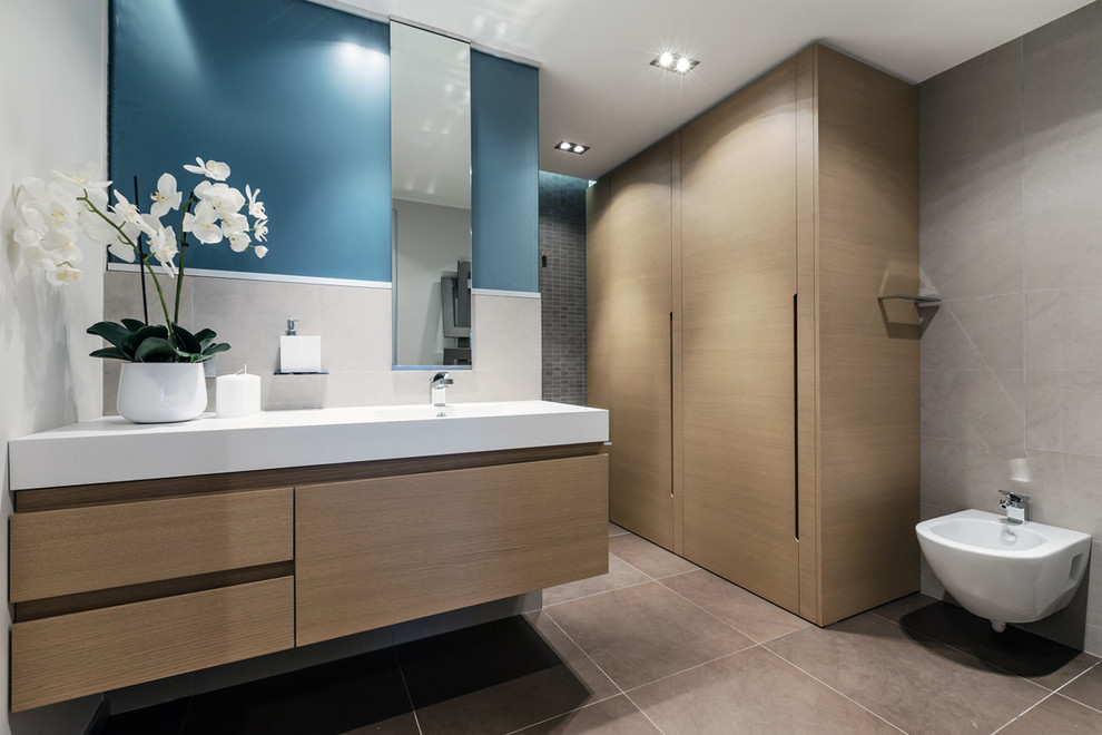 Design ideas for a contemporary bathroom in Other with flat-panel cabinets, light wood cabinets, a wall-mount toilet, white walls and an integrated sink.