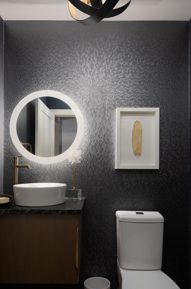 Inredning av ett klassiskt litet svart svart badrum med dusch, med släta luckor, svart kakel, svarta väggar, mörkt trägolv, ett fristående handfat och granitbänkskiva