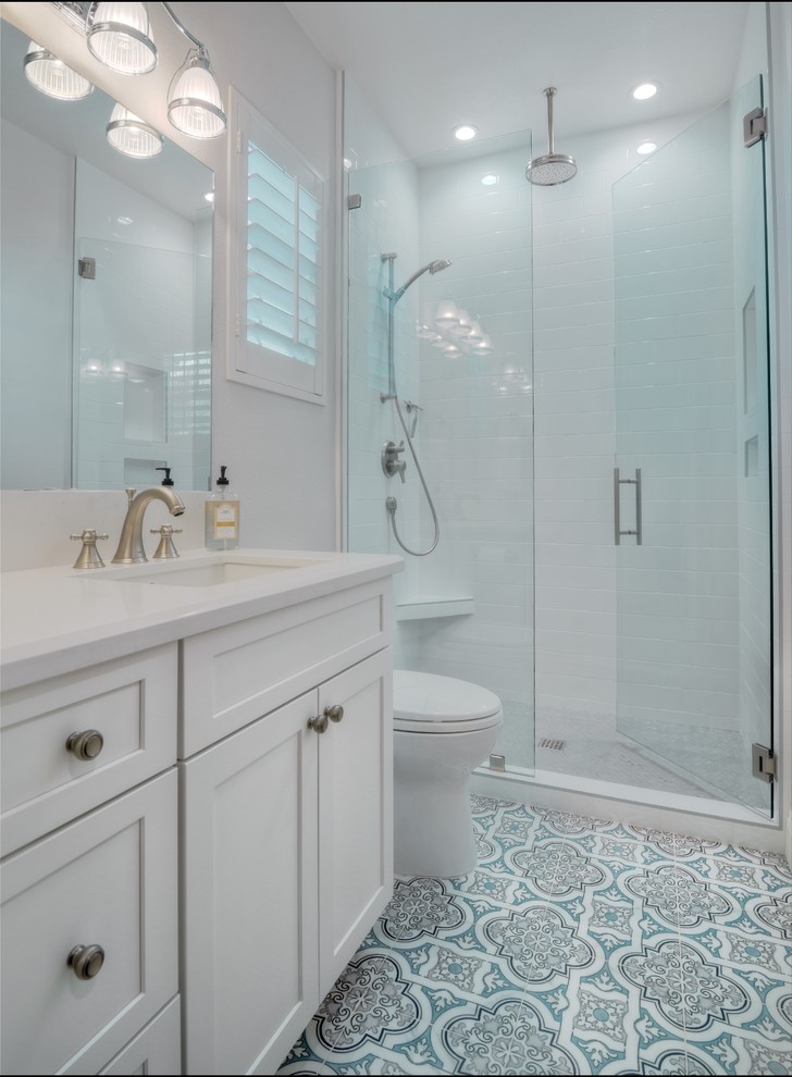 This is an example of a mid-sized beach style master bathroom in San Diego with shaker cabinets, white cabinets, a freestanding tub, an alcove shower, white tile, ceramic tile, grey walls, porcelain floors, an undermount sink and engineered quartz benchtops.