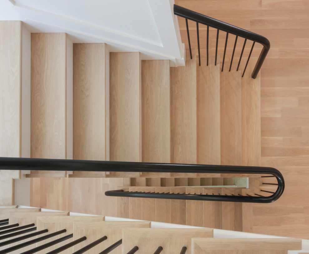 This is an example of a large modern wood u-shaped mixed railing staircase in DC Metro with painted wood risers and wainscoting.