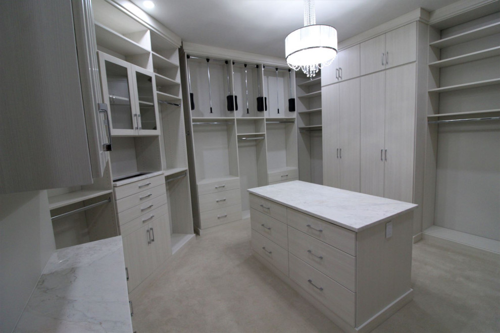 Photo of a large transitional women's walk-in wardrobe in Indianapolis with glass-front cabinets, beige cabinets, carpet and beige floor.