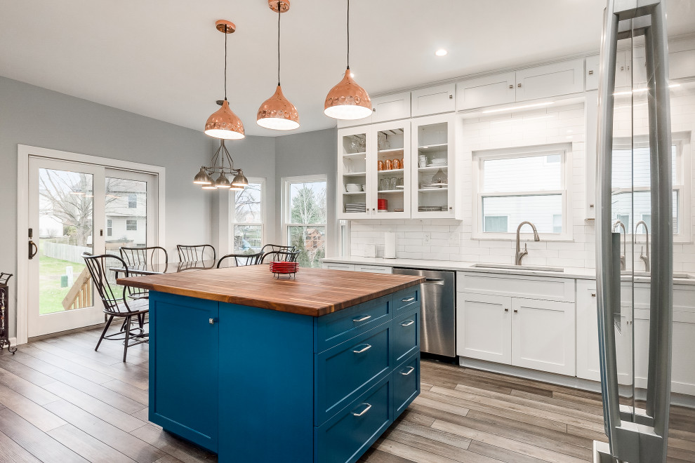 Example of a mid-sized transitional l-shaped eat-in kitchen design in Columbus with shaker cabinets, quartz countertops, white backsplash, subway tile backsplash and an island
