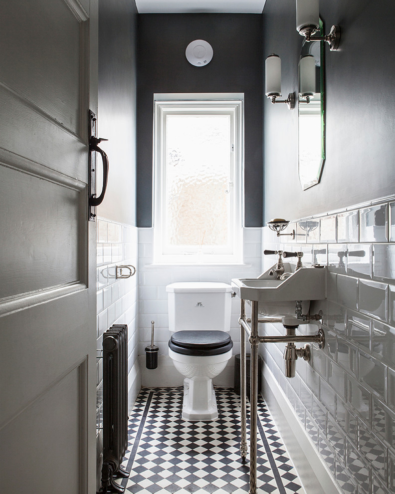 Inspiration for a small traditional powder room in Sussex with grey walls, porcelain floors, black and white tile, white tile, a console sink, a two-piece toilet and multi-coloured floor.