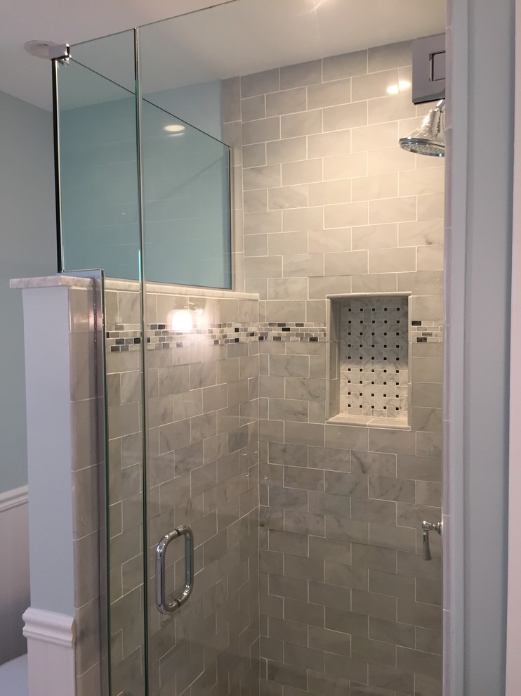 Photo of a mid-sized contemporary bathroom in New York with white cabinets, a corner shower, blue walls, an undermount sink and marble benchtops.