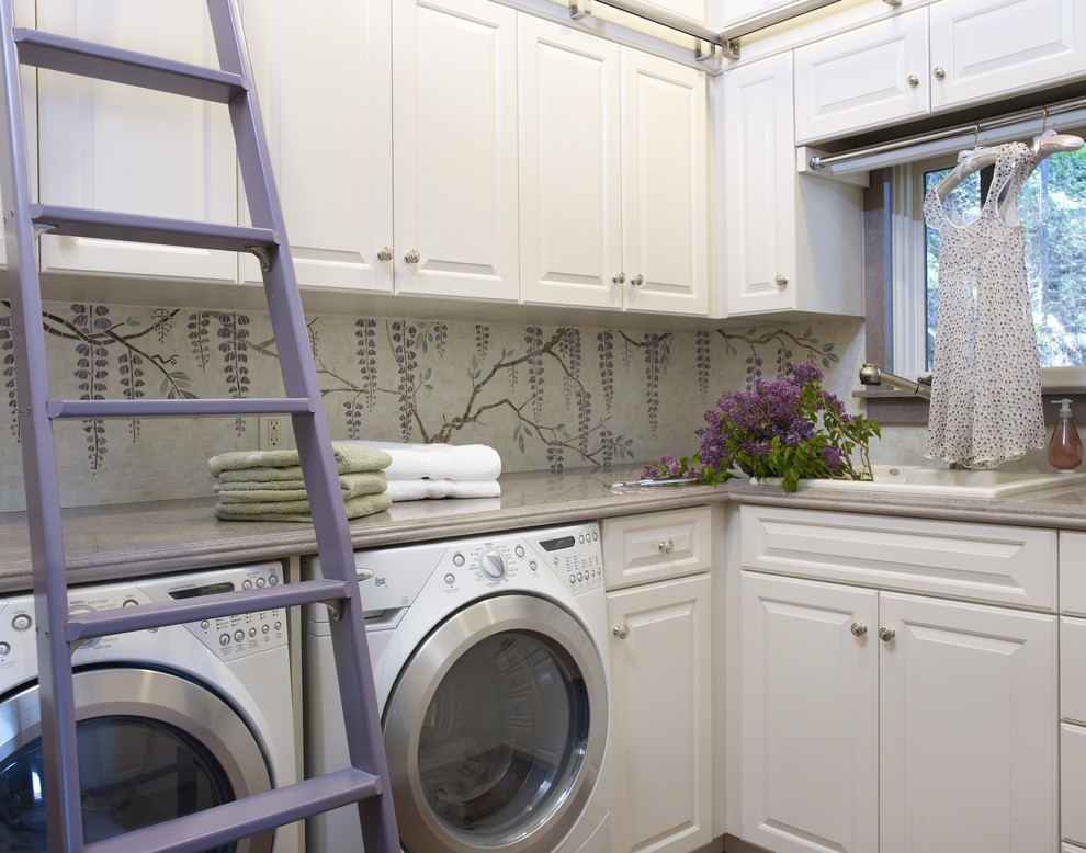 Design ideas for a large mediterranean l-shaped dedicated laundry room in Los Angeles with a drop-in sink, raised-panel cabinets, white cabinets, granite benchtops, multi-coloured walls and a side-by-side washer and dryer.