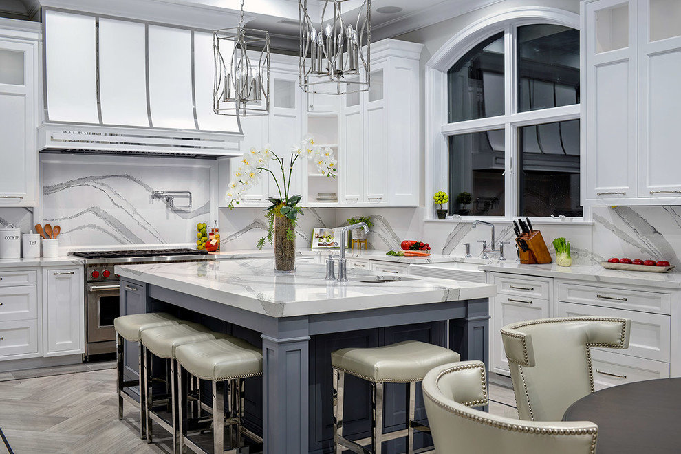 Photo of a transitional l-shaped eat-in kitchen in New York with a farmhouse sink, recessed-panel cabinets, stainless steel appliances, with island, grey floor and white benchtop.