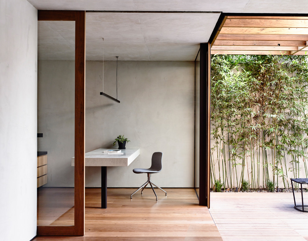 Photo of a small modern home office in Melbourne with grey walls and medium hardwood floors.