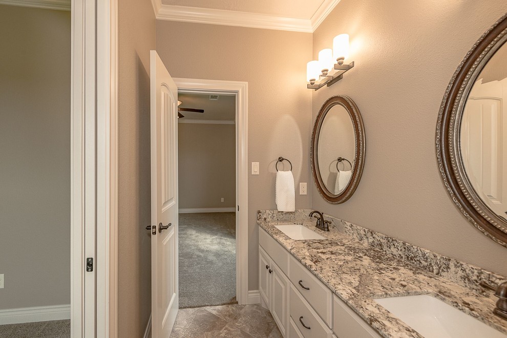 Photo of a mid-sized country 3/4 bathroom in Austin with shaker cabinets, medium wood cabinets, an alcove tub, a shower/bathtub combo, a two-piece toilet, brown tile, travertine, beige walls, brick floors, an undermount sink, granite benchtops, brown floor and an open shower.