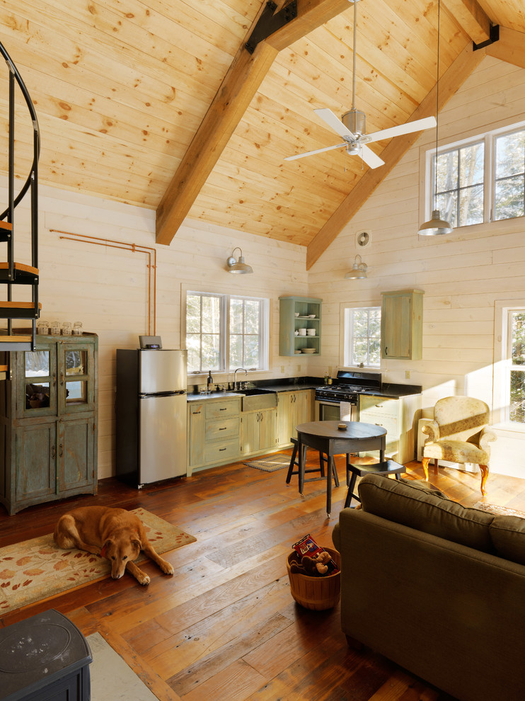 Inspiration for a small country l-shaped open plan kitchen in Burlington with green cabinets, stainless steel appliances, medium hardwood floors, no island, a farmhouse sink, soapstone benchtops, black splashback and flat-panel cabinets.