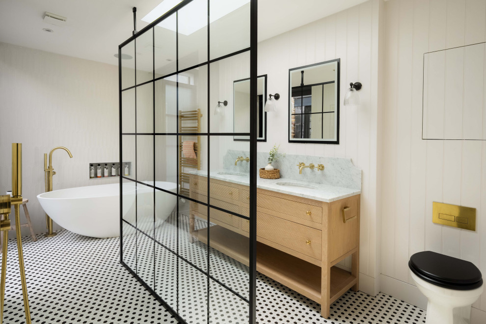 This is an example of a classic ensuite bathroom with flat-panel cabinets, light wood cabinets, a freestanding bath, a built-in shower, a one-piece toilet, white tiles, white walls, mosaic tile flooring, a submerged sink, multi-coloured floors, an open shower, grey worktops, double sinks, a freestanding vanity unit and tongue and groove walls.