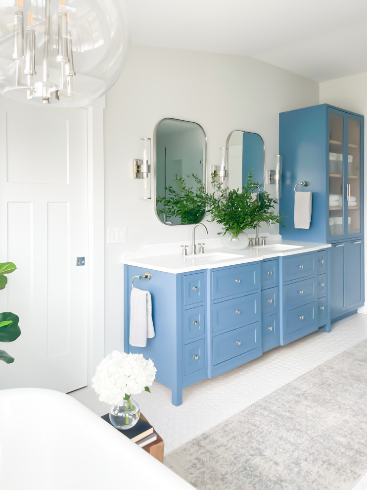 Пример оригинального дизайна: большая главная ванная комната со стиральной машиной в стиле неоклассика (современная классика) с фасадами в стиле шейкер, синими фасадами, ванной на ножках, душем в нише, белой плиткой, керамической плиткой, серыми стенами, полом из керамической плитки, врезной раковиной, столешницей из искусственного кварца, белым полом, душем с распашными дверями, белой столешницей, тумбой под две раковины, встроенной тумбой и сводчатым потолком