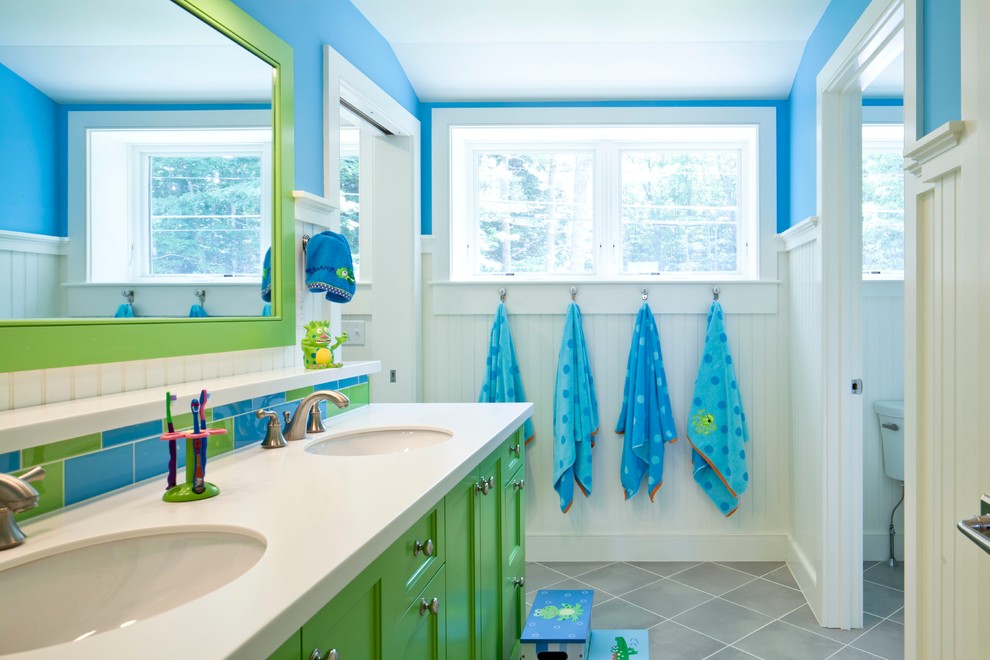 This is an example of a beach style kids bathroom in Portland Maine with green cabinets, multi-coloured tile, ceramic floors, an undermount sink, recessed-panel cabinets, stone tile and blue walls.