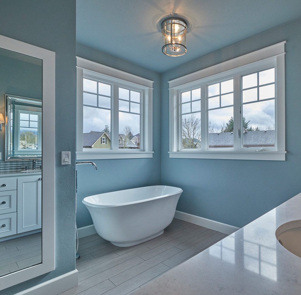 Design ideas for a mid-sized arts and crafts master bathroom in Portland with shaker cabinets, white cabinets, a freestanding tub, an open shower, a one-piece toilet, multi-coloured tile, glass tile, blue walls, porcelain floors, an undermount sink, grey floor and a hinged shower door.