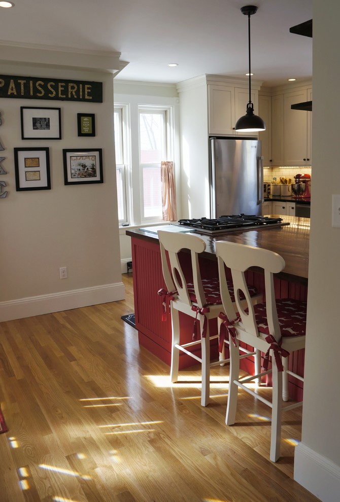 Inspiration for a small rustic l-shaped light wood floor and beige floor enclosed kitchen remodel in Boston with an undermount sink, recessed-panel cabinets, granite countertops, white backsplash, subway tile backsplash, stainless steel appliances, an island, white cabinets and black countertops