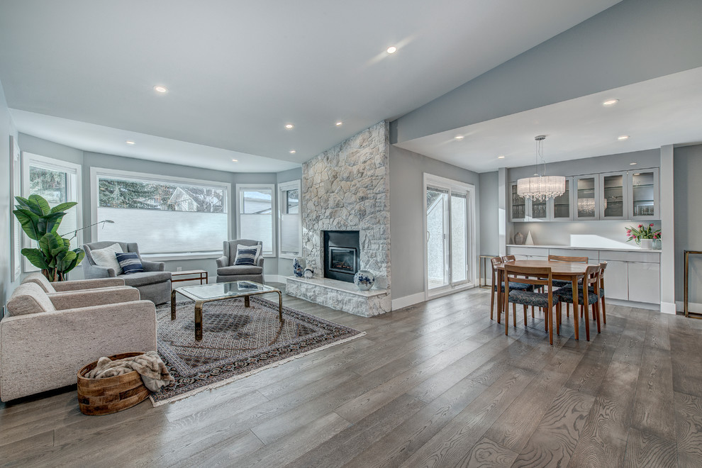 Design ideas for a mid-sized contemporary open concept family room in Calgary with grey walls, vinyl floors, a standard fireplace, a stone fireplace surround and grey floor.