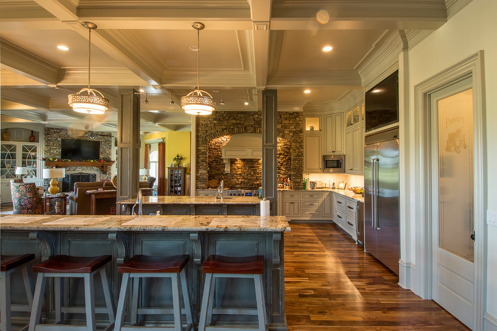 Eat-in kitchen - large rustic u-shaped medium tone wood floor and brown floor eat-in kitchen idea with an undermount sink, raised-panel cabinets, distressed cabinets, granite countertops, brown backsplash, stone tile backsplash, stainless steel appliances, two islands and multicolored countertops