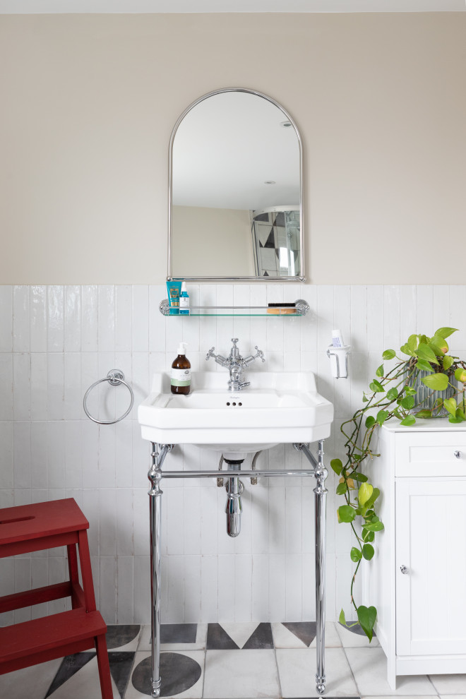 Mid-sized traditional bathroom in London with shaker cabinets, white cabinets, a freestanding tub, a corner shower, a one-piece toilet, white tile, porcelain tile, porcelain floors, a wall-mount sink, multi-coloured floor, a sliding shower screen, white benchtops, white walls, a single vanity and a freestanding vanity.