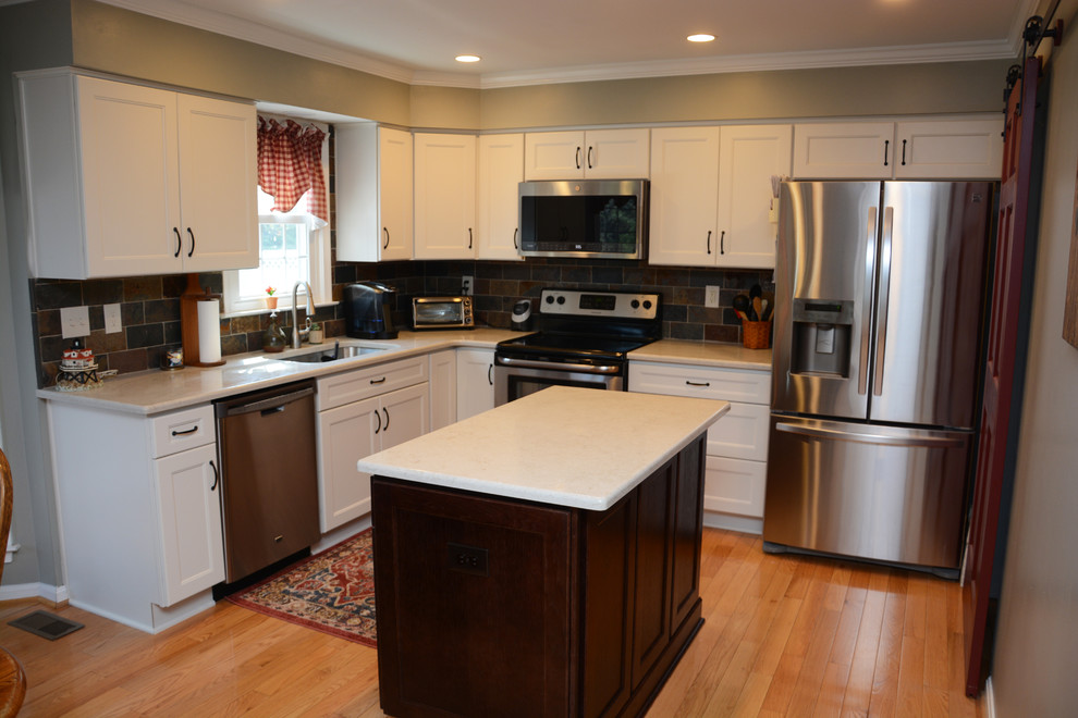 This is an example of a small l-shaped eat-in kitchen in DC Metro with an undermount sink, recessed-panel cabinets, white cabinets, quartz benchtops, multi-coloured splashback, slate splashback, stainless steel appliances, light hardwood floors, with island, brown floor and white benchtop.
