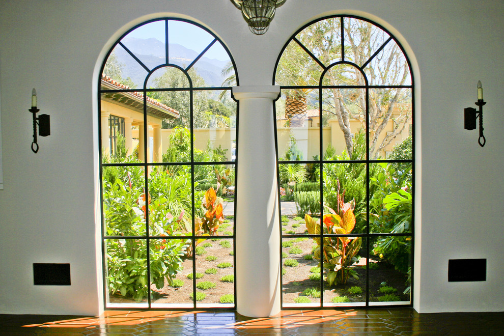 Photo of a large mediterranean hallway in Santa Barbara with white walls and terra-cotta floors.