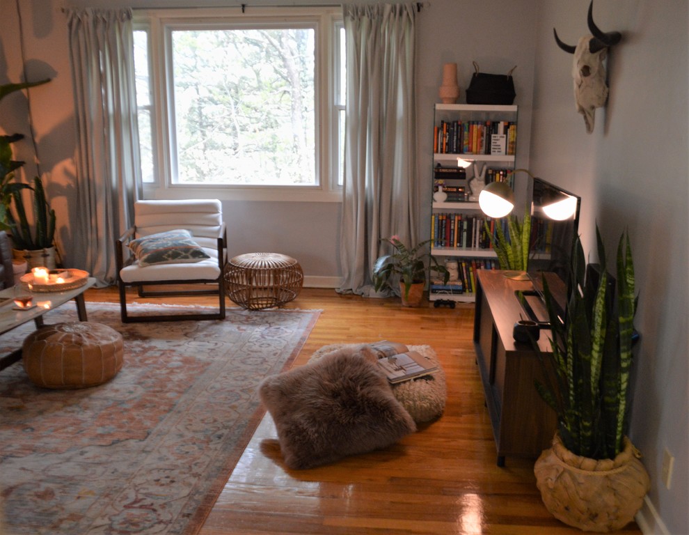 This is an example of a mid-sized eclectic living room in New York with grey walls, medium hardwood floors, no fireplace and brown floor.