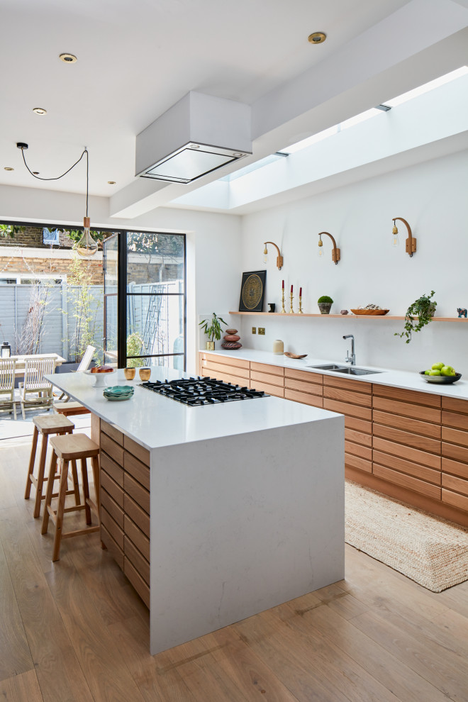 This is an example of a mid-sized scandinavian open plan kitchen in London with solid surface benchtops and with island.