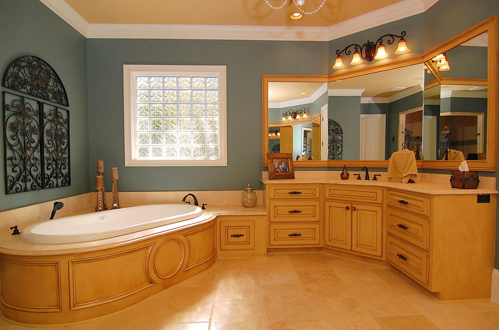 Inspiration for a large traditional master bathroom in Charleston with raised-panel cabinets, yellow cabinets, a drop-in tub, a corner shower, beige tile, blue walls, ceramic floors, an undermount sink, granite benchtops, beige floor and a hinged shower door.